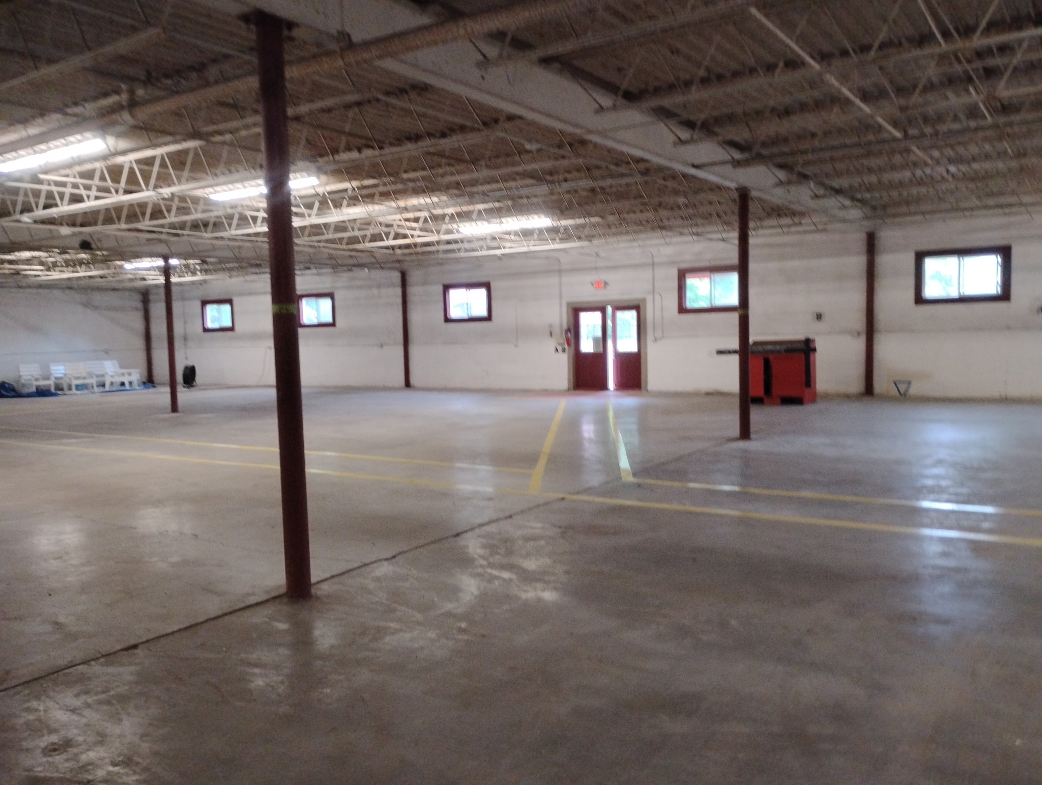 Warehouse interior with open concrete floor, support columns, and red exit doors